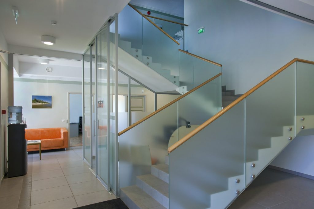 A traditional house with a modern glass extension, two storeys, with glass walls.