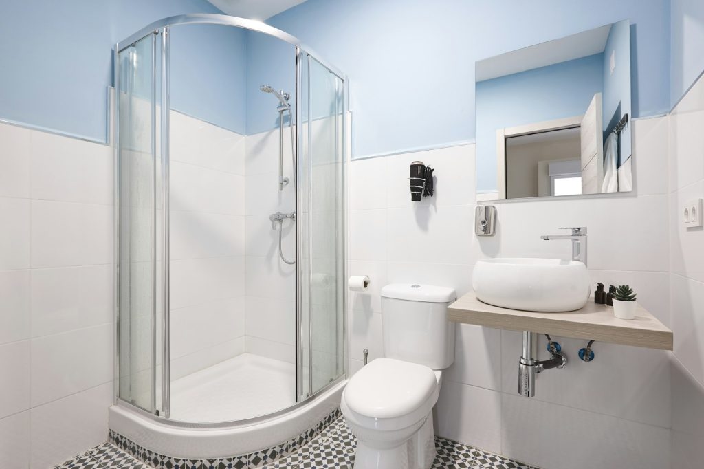 Bathroom with shower cabin, sink and basin. Modern apartment